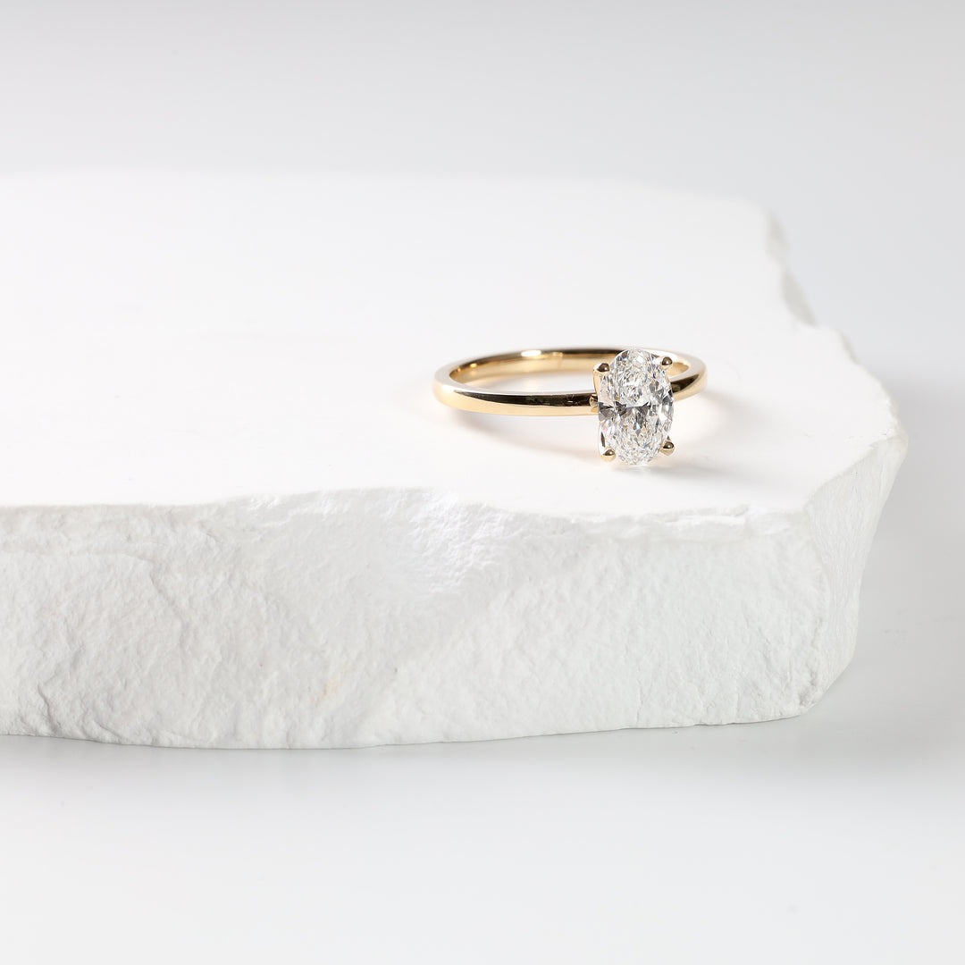 Oval lab-grown diamond solitaire ring in 18K yellow gold, three-quarter view on a white background.