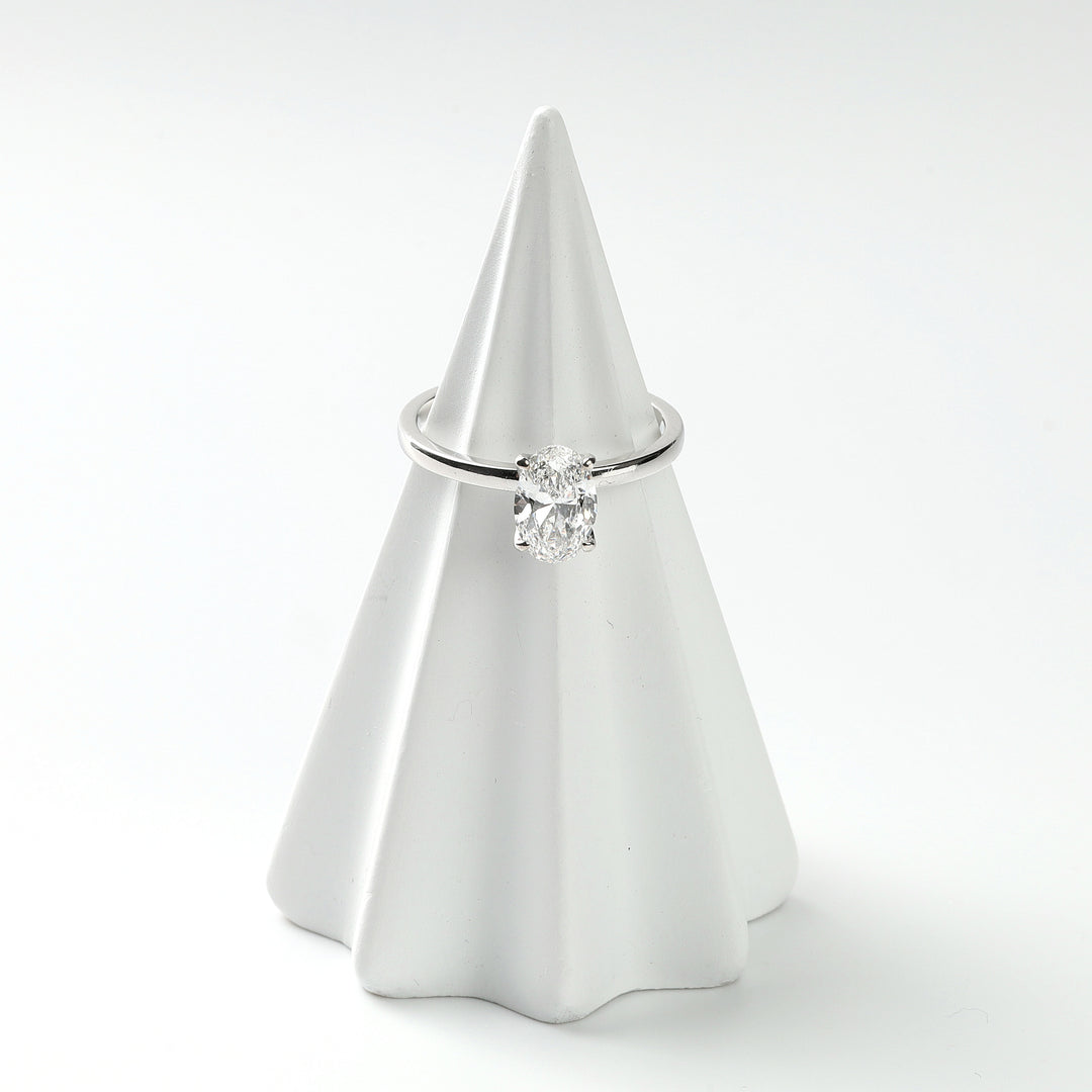 Oval lab-grown diamond solitaire in 14K white gold displayed on a white cone ring stand, front view.