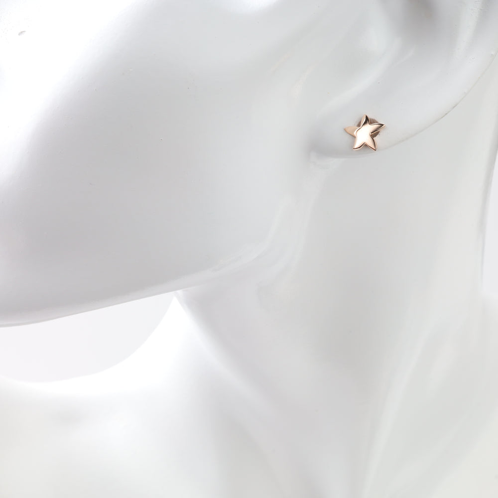 Rose gold star stud earring shown on an ear display