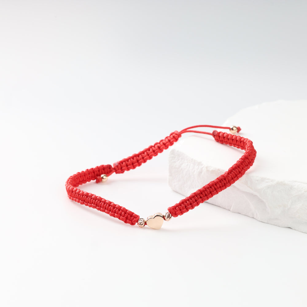 Red woven cord bracelet with polished rose gold heart on white stone