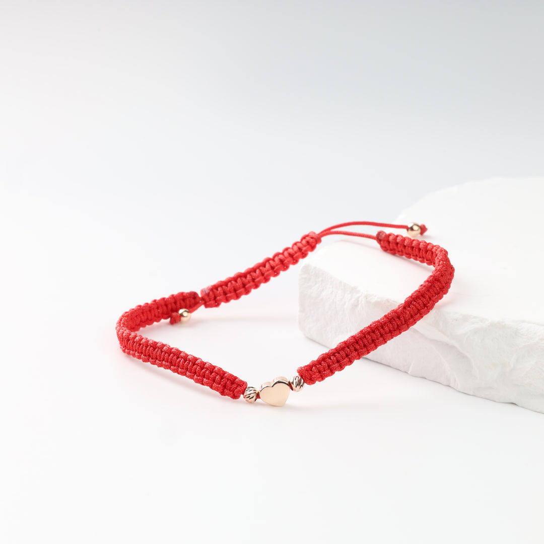 Red woven cord bracelet with polished rose gold heart on white stone