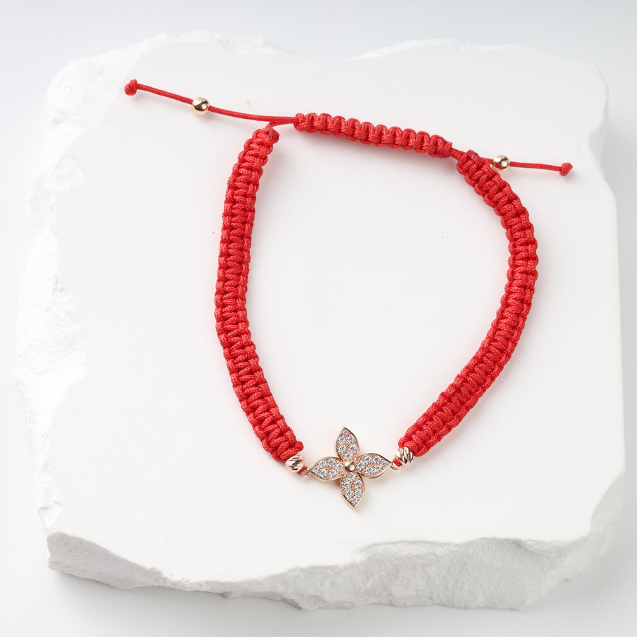 Adjustable red cord bracelet with rose gold flower and clear cubic zirconia, front view