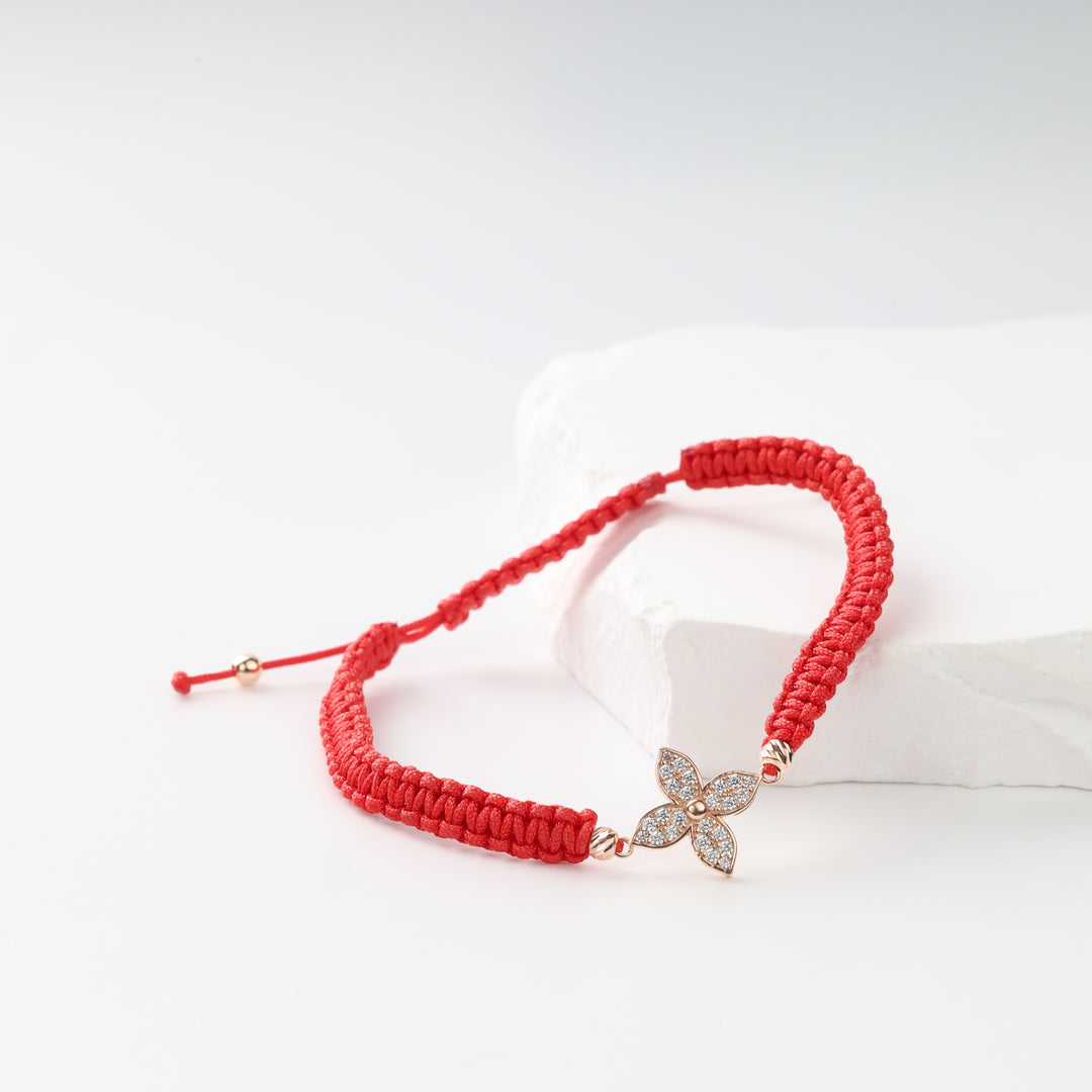 Red woven cord bracelet with four-petal zircon flower on white stone
