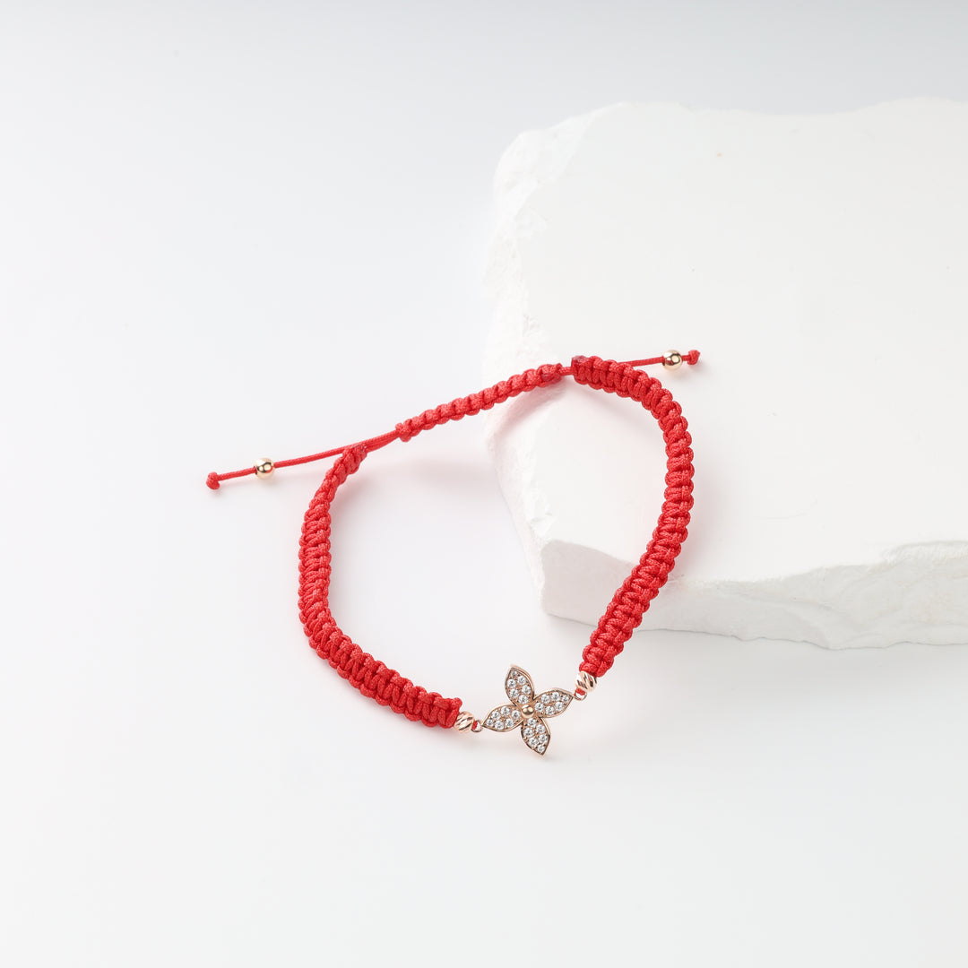 Full view of adjustable red cord flower bracelet with sliding closure