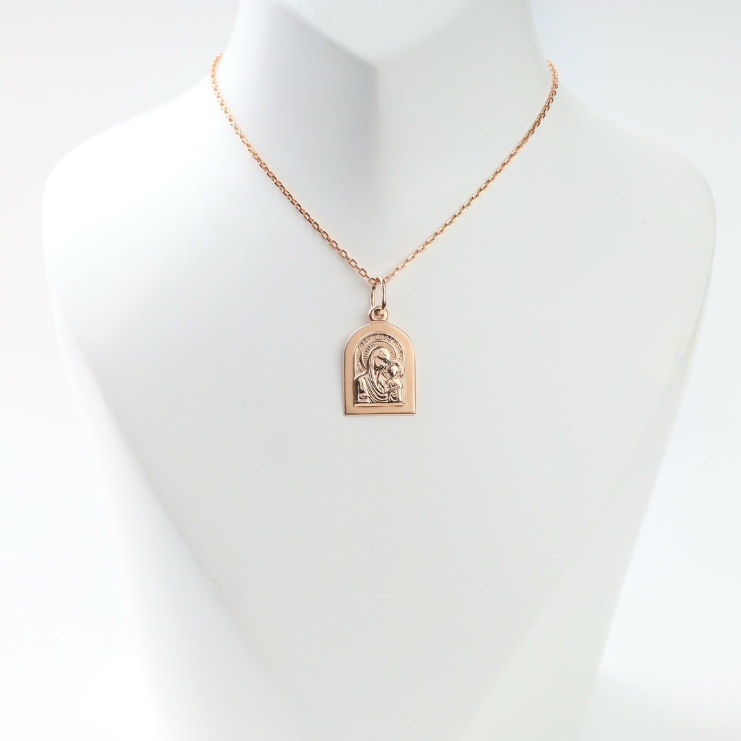Rose gold Madonna and Child pendant displayed on a necklace bust
