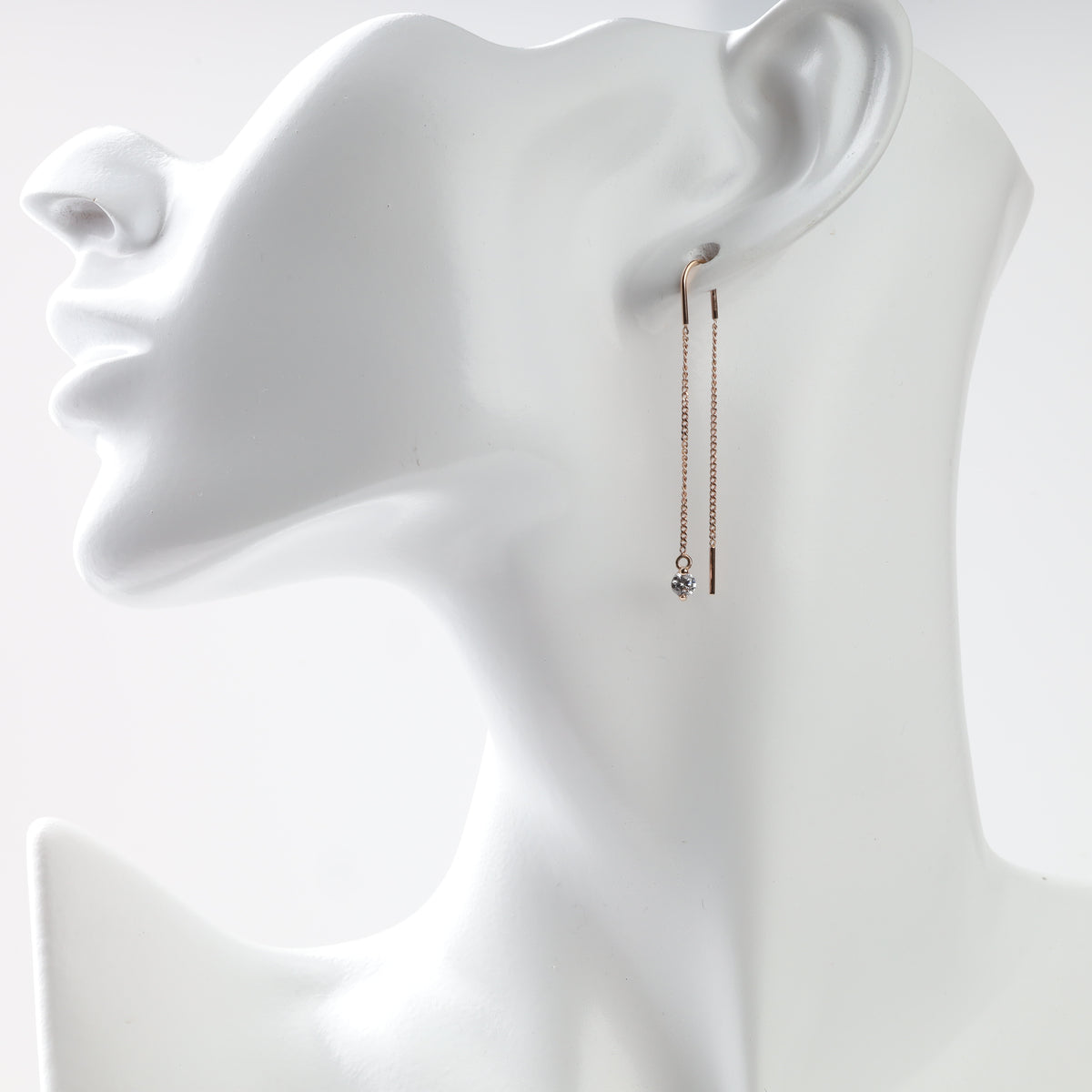 Rose gold threader earring worn on a display head, stone hanging in front of the ear