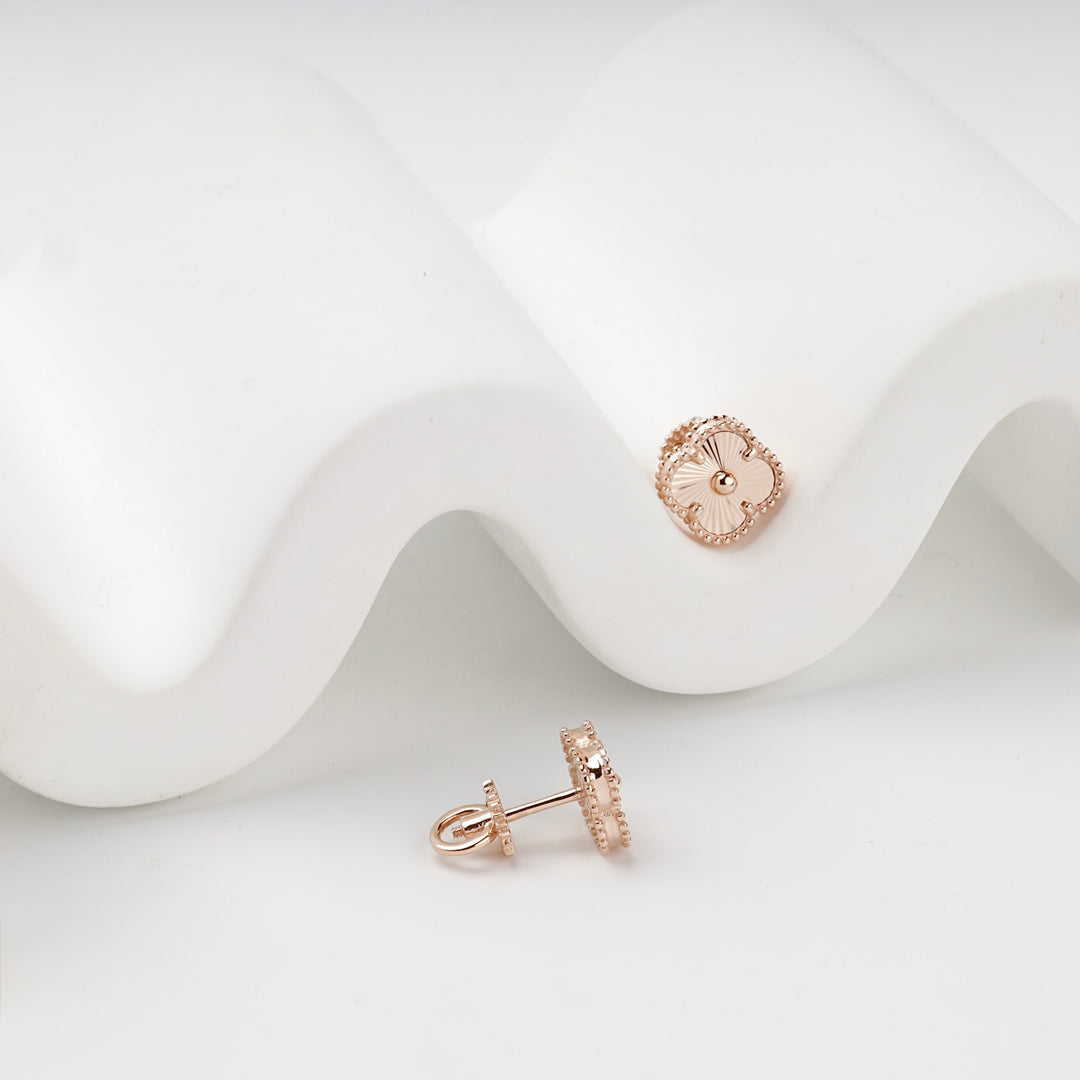 Rose gold clover stud earrings pair on white surface