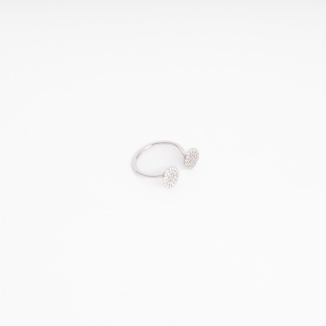 Open silver ring showing the thin band and two cubic zirconia discs at the tips, angled view