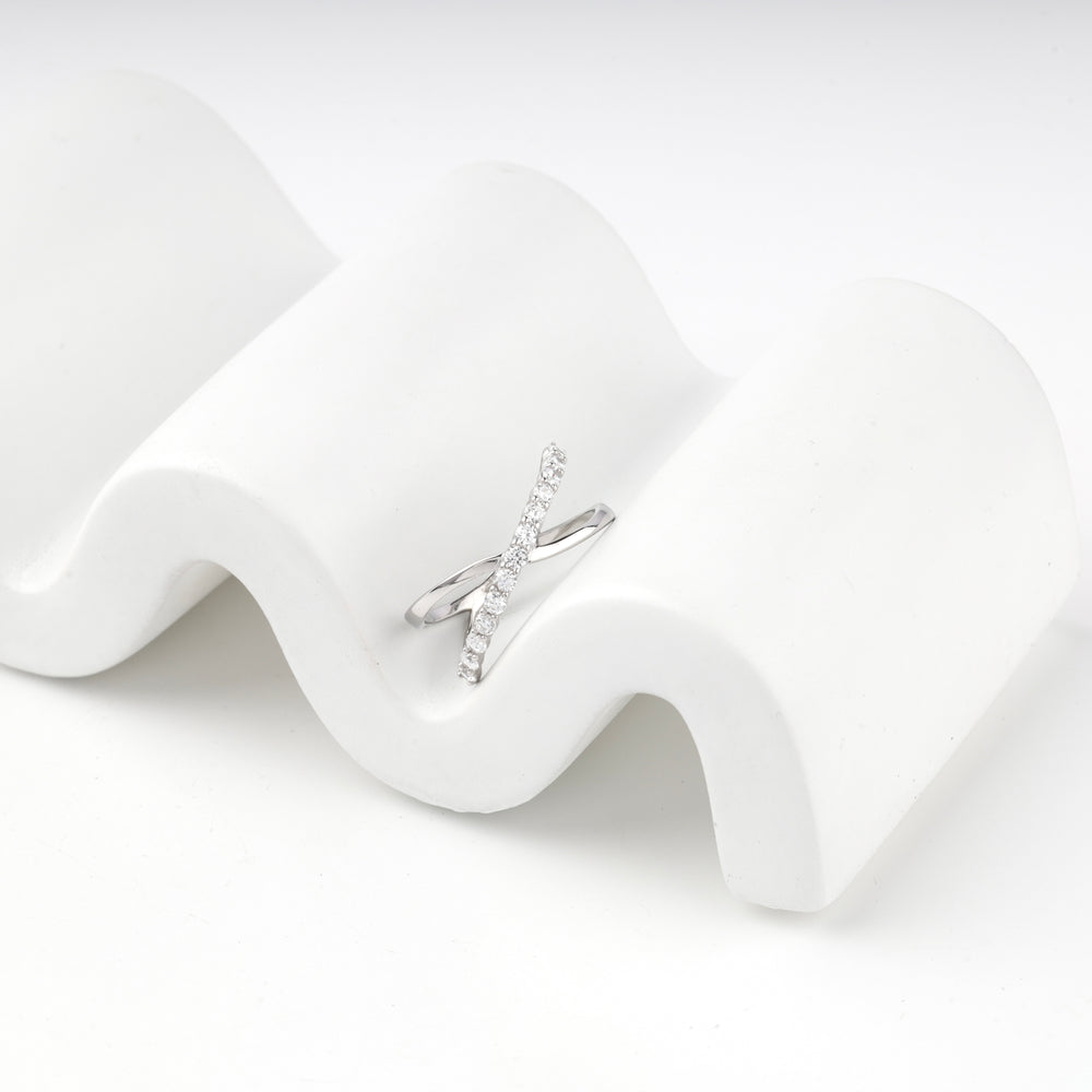 Silver 925 crossover ring resting on a wavy white display block