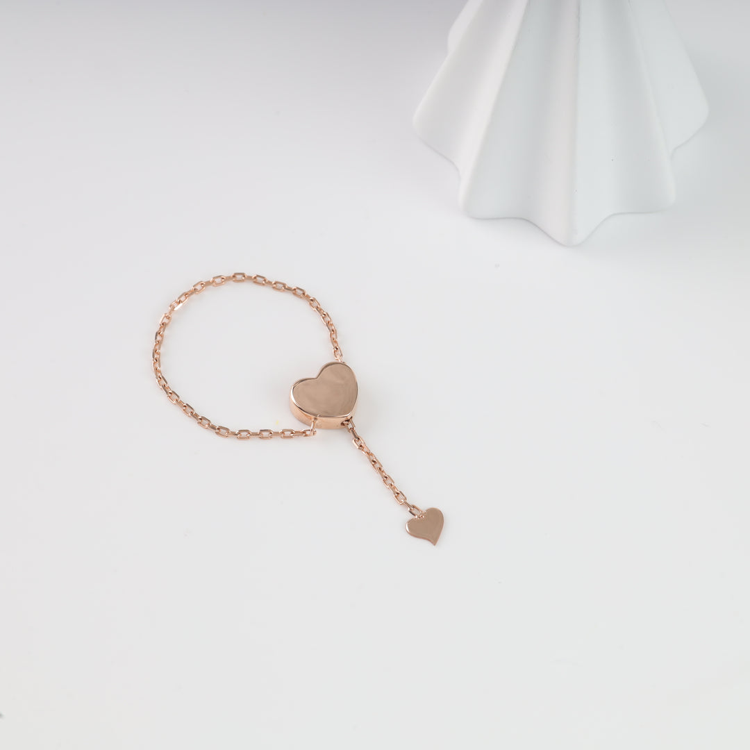 Rose gold heart chain ring laid flat, showing the chain band and hanging heart charm