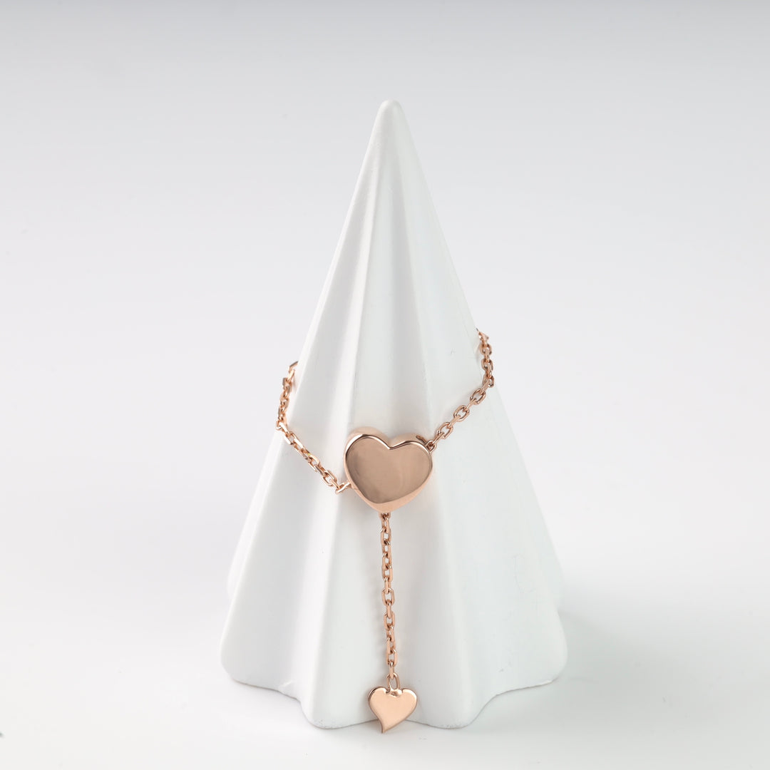 Front view of the rose gold heart chain ring on a white display cone