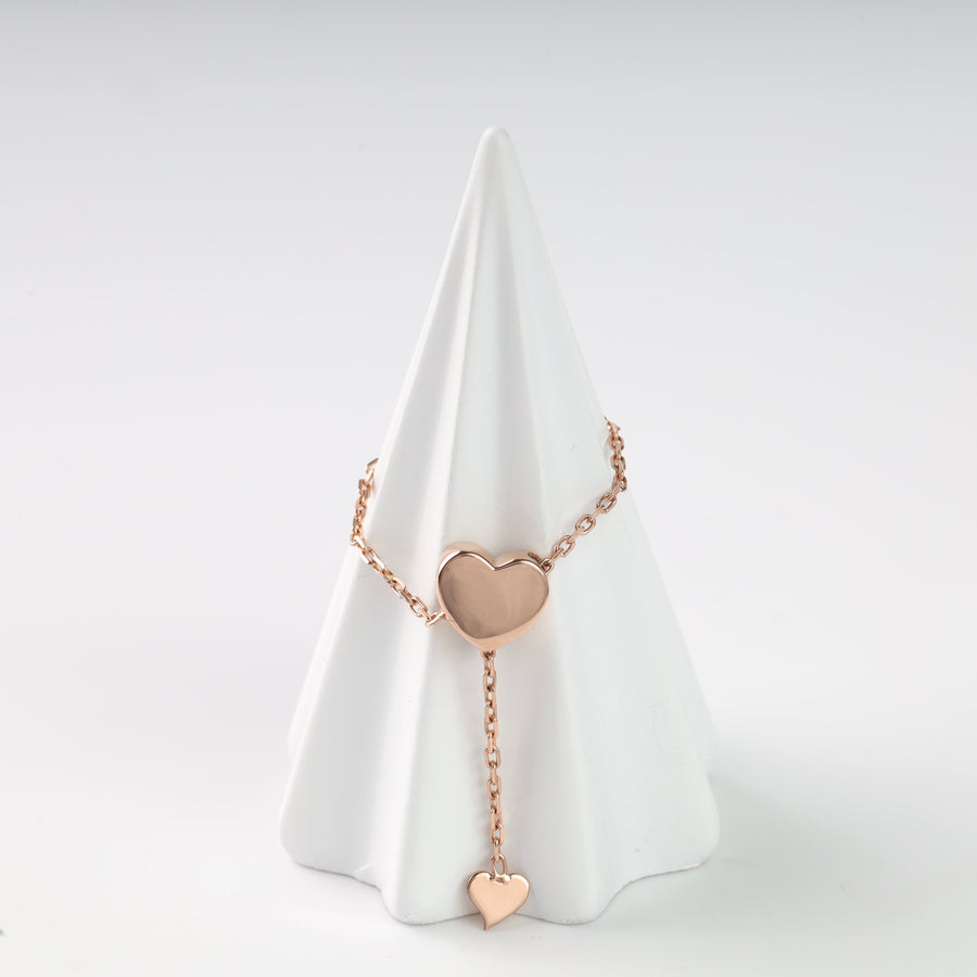 Front view of the rose gold heart chain ring on a white display cone