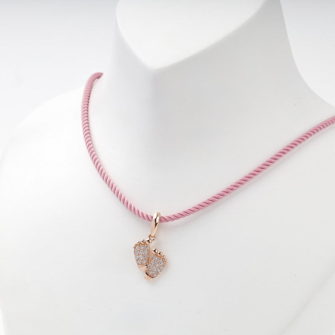 Rose gold baby feet pendant on a pink cord, worn view