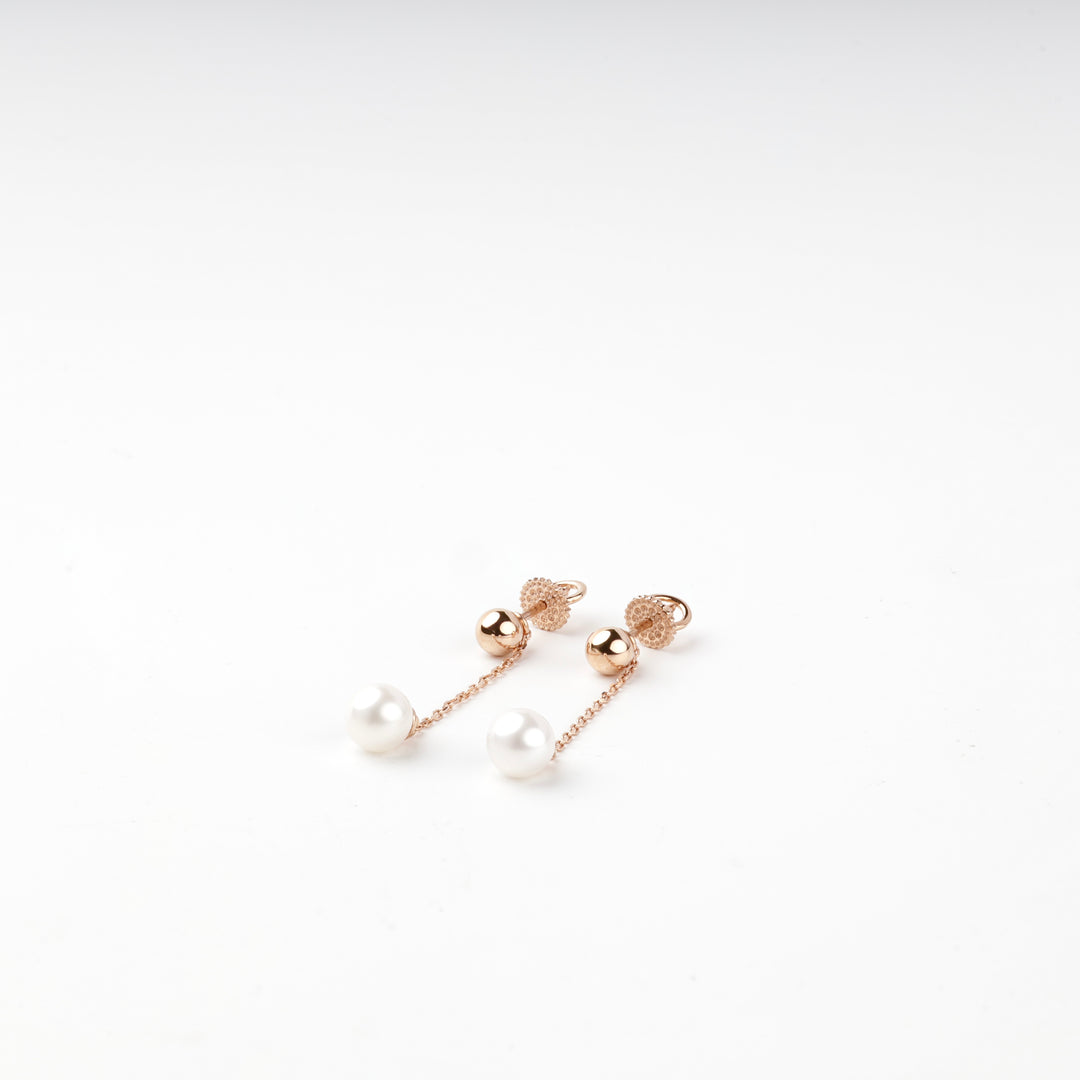 Rose gold 585 earrings with white pearl drops on fine chains, angled view