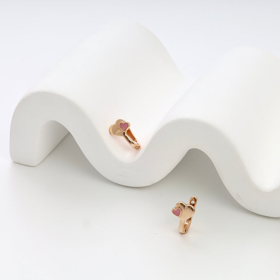 Pair of rose gold heart hoop earrings with pink enamel, displayed on white stand, Ukrainian Jewelry, kids gold earrings gift.