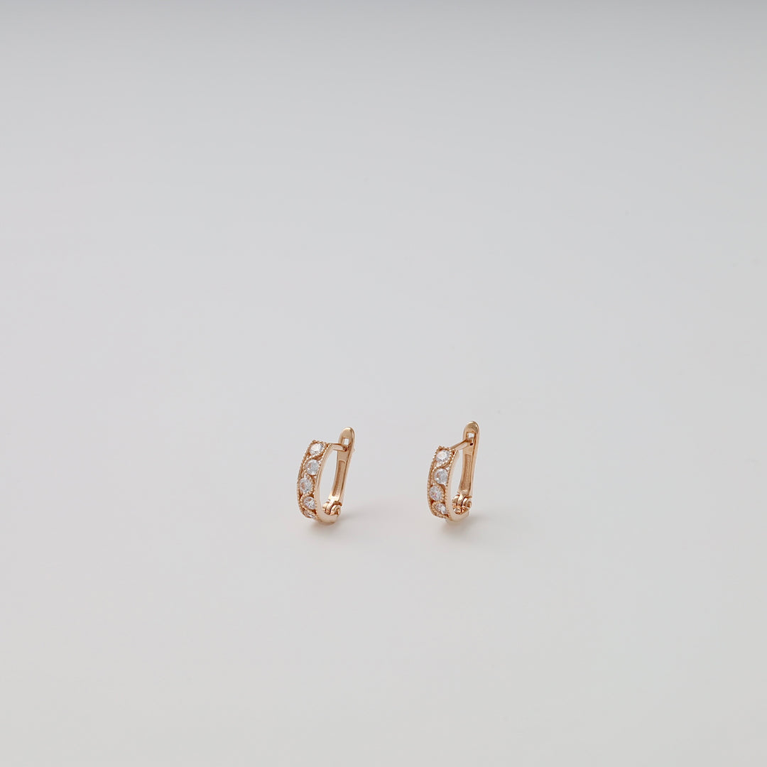14k gold huggie earrings with small white stones on a plain background, classic hoop Ukrainian Jewelry for women.