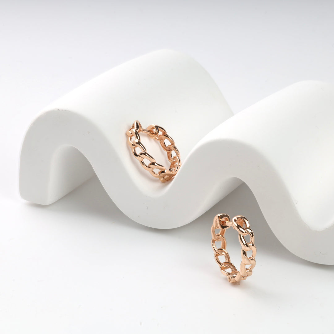 Rose gold chain link hoop earrings on a white wave display.