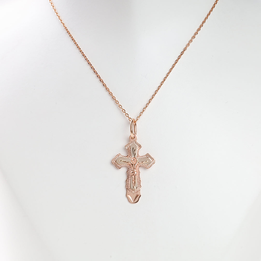 Rose gold crucifix pendant necklace with a detailed cross motif displayed on a simple chain. Cross pendant, religious jewelry.