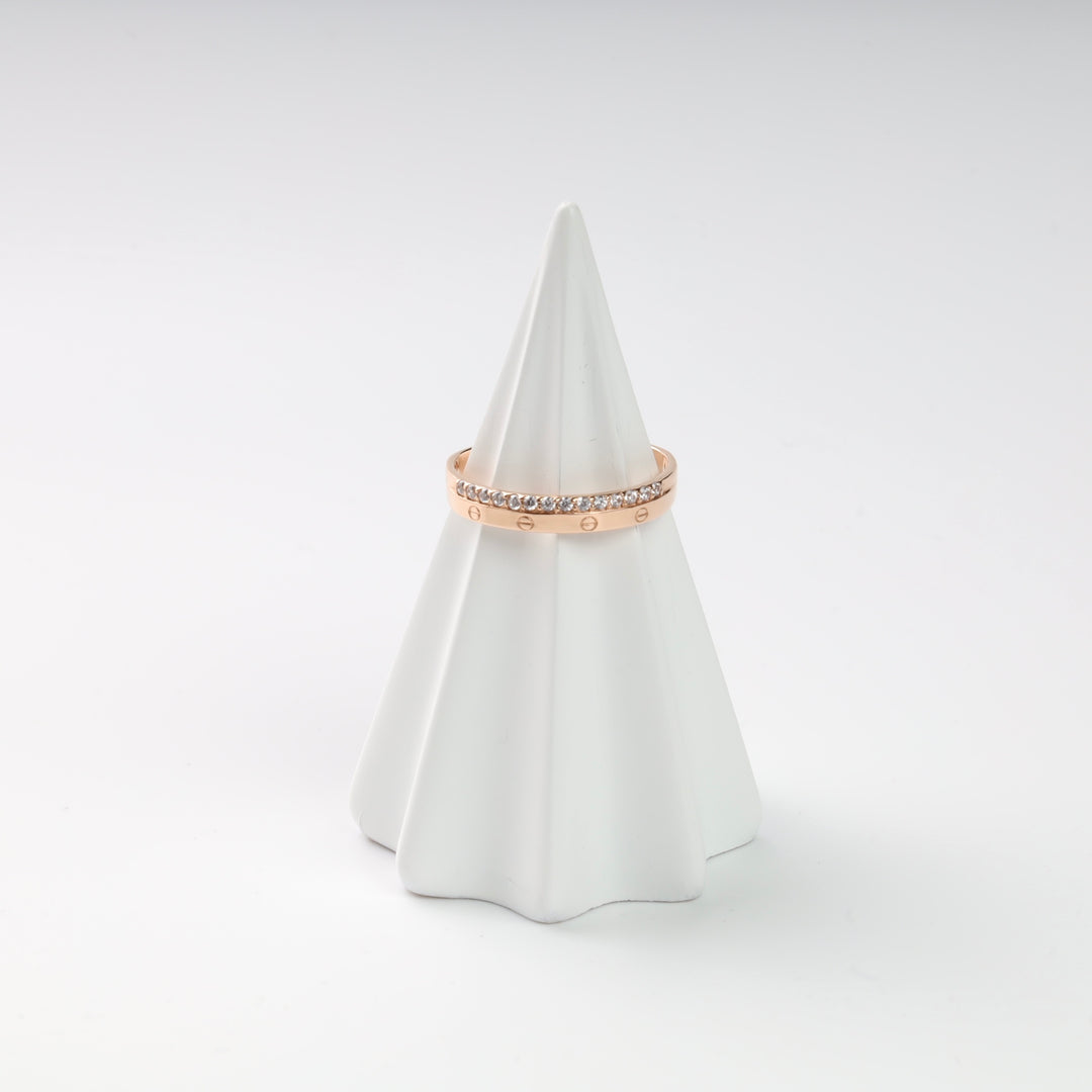 Rose gold band ring with crystal accents displayed on a white cone.