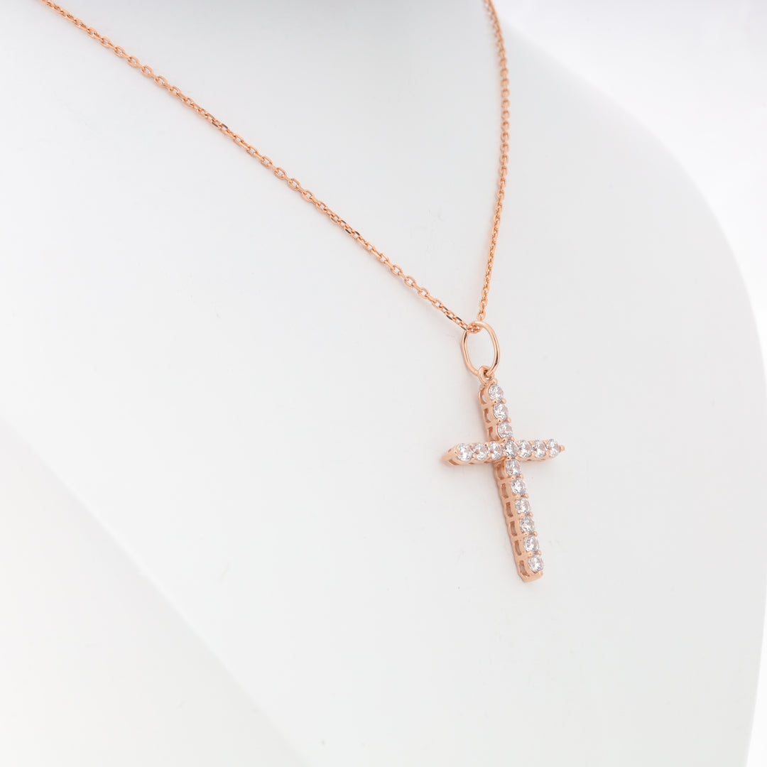 Rose gold chain necklace with a crystal-studded cross pendant displayed on a white mannequin. Cross necklace, rose gold, crystal.