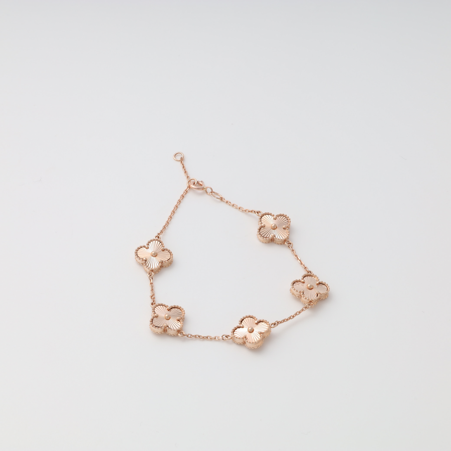 Rose gold bracelet with five flower-shaped charms on a chain, displayed on a white background.