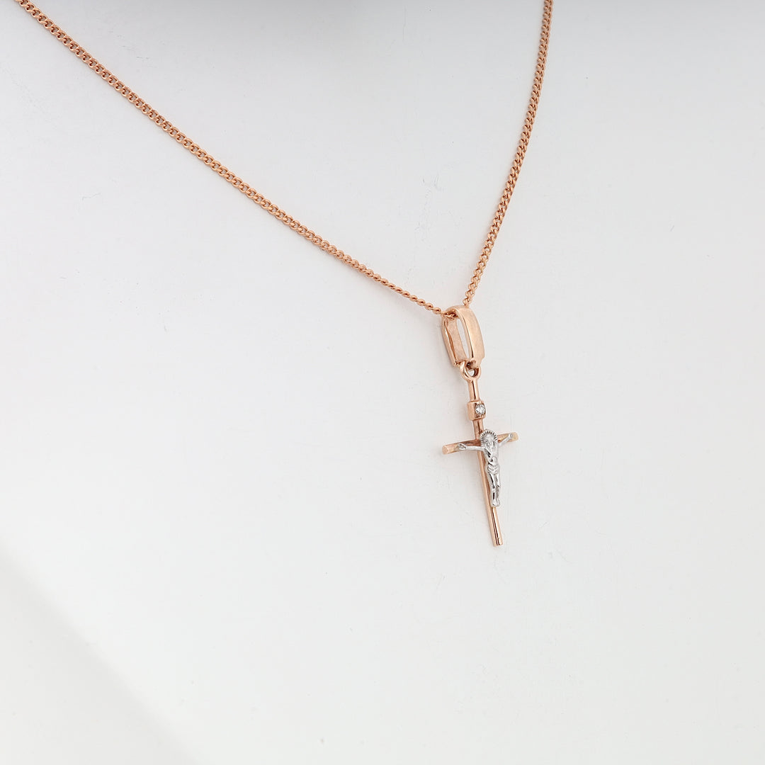 Gold chain necklace with a crucifix pendant in silver and gold tones against a plain white background.