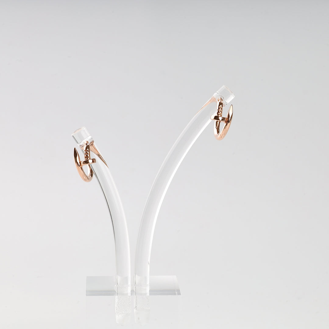 Pair of small rose gold hoop earrings with a twist motif displayed on a clear acrylic stand.
