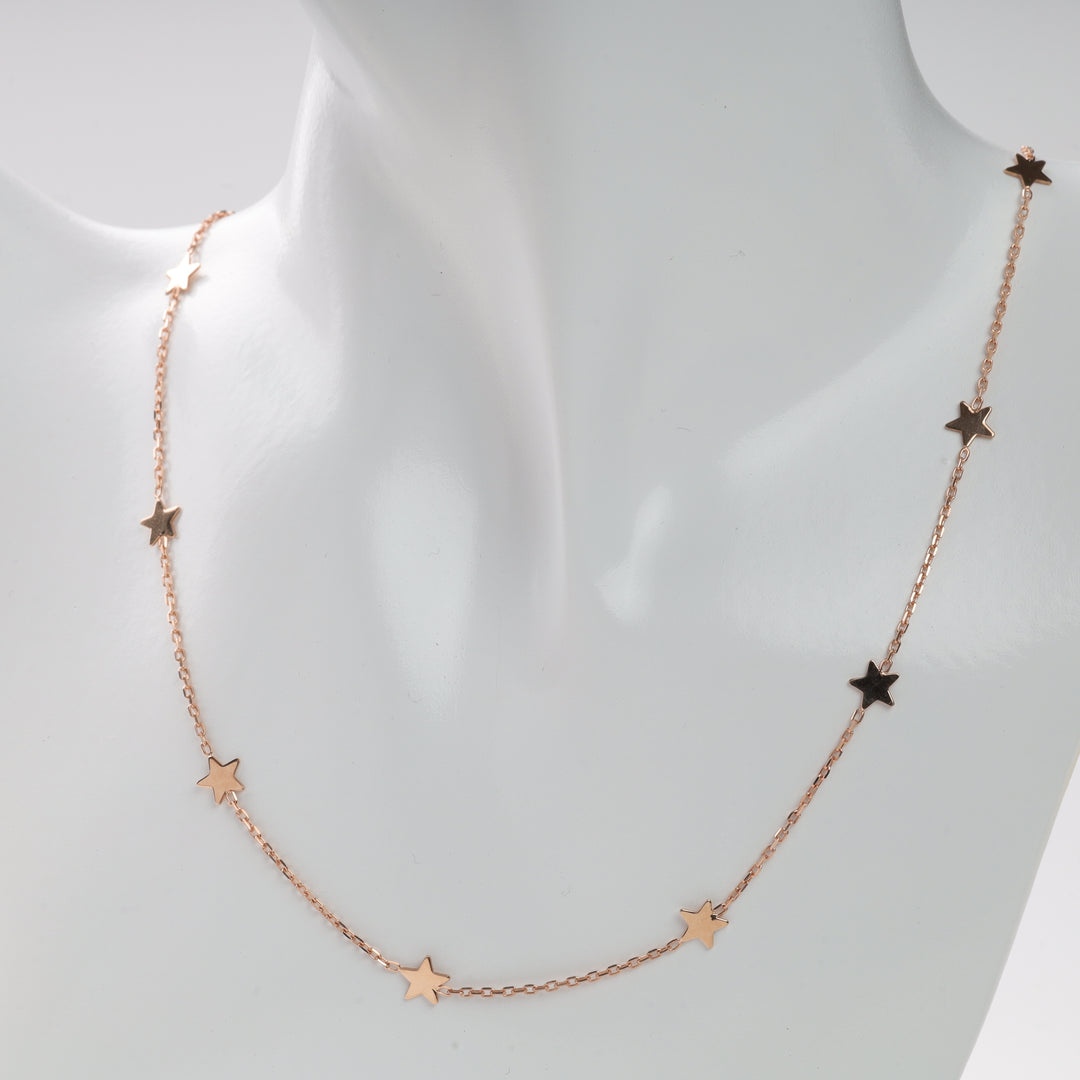 Rose gold chain necklace with small star charms displayed on a white bust.