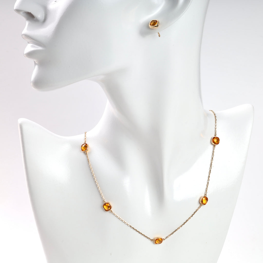 Gold chain necklace and stud earring with amber gemstones displayed on white mannequin.