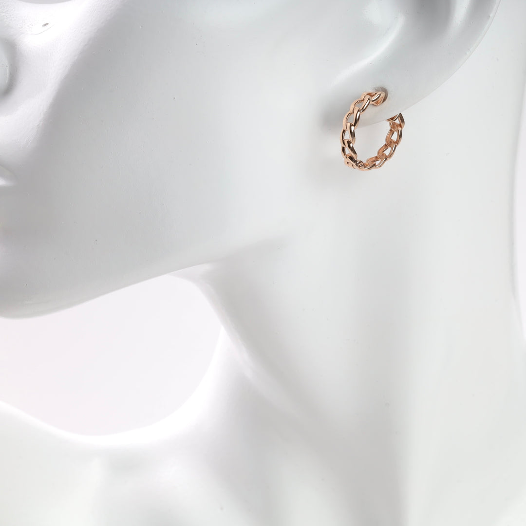 Rose gold twisted hoop earring on a white display mannequin.