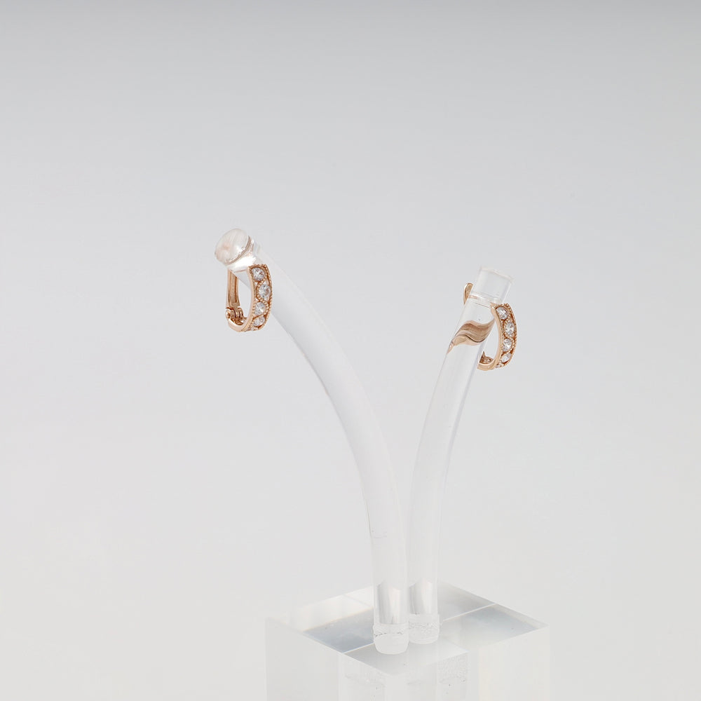 14k gold huggie hoop earrings with small white stones on a clear stand, elegant Ukrainian Jewelry for everyday gold hoop earring shoppers.
