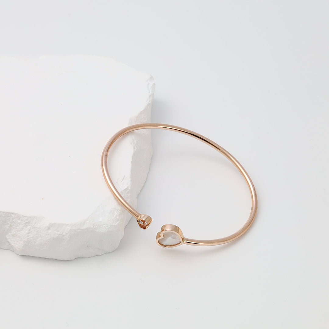 Rose gold plated bracelet with heart charm and crystal accent on white stone display, Ukrainian Jewelry, minimalist gold bangle bracelet.