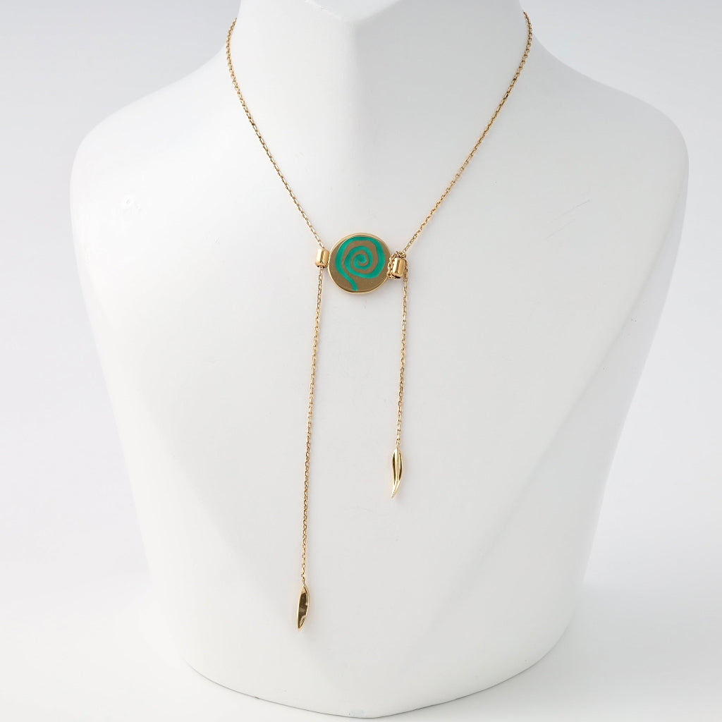 Gold lariat necklace with green spiral disc pendant and drop charms on display bust, Ukrainian Jewelry, dainty gold pendant necklace.