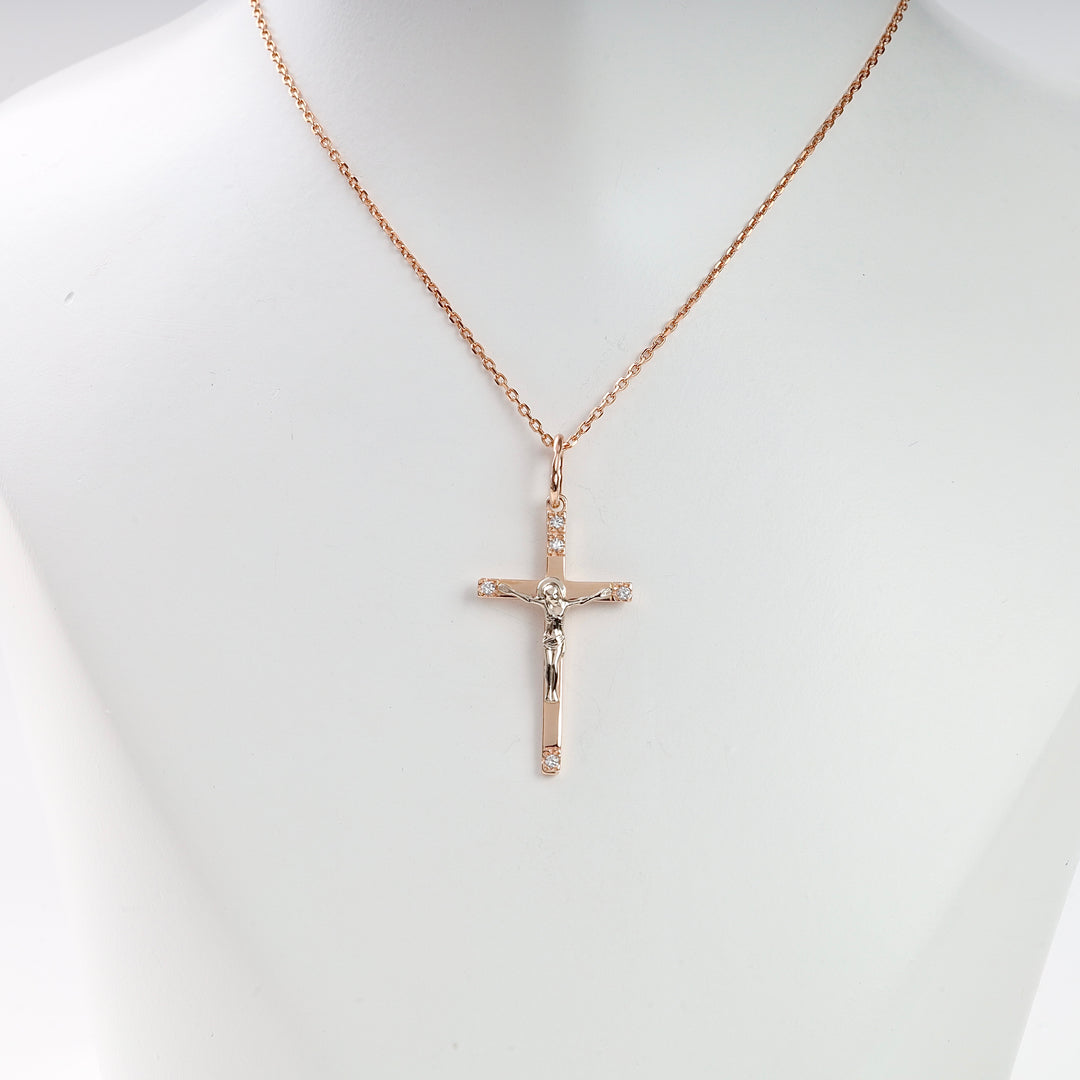 Gold crucifix necklace with Jesus figure and small clear stones on a delicate chain, displayed on a white bust.