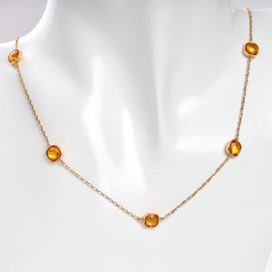 Gold necklace with five amber gemstones displayed on a mannequin.