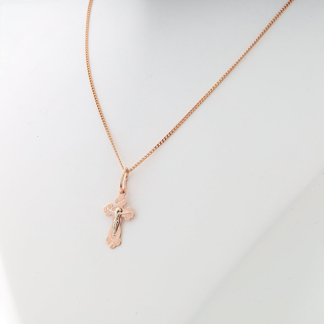 Rose gold cross pendant necklace with religious motif displayed on a white mannequin. Cross necklace, rose gold jewelry.
