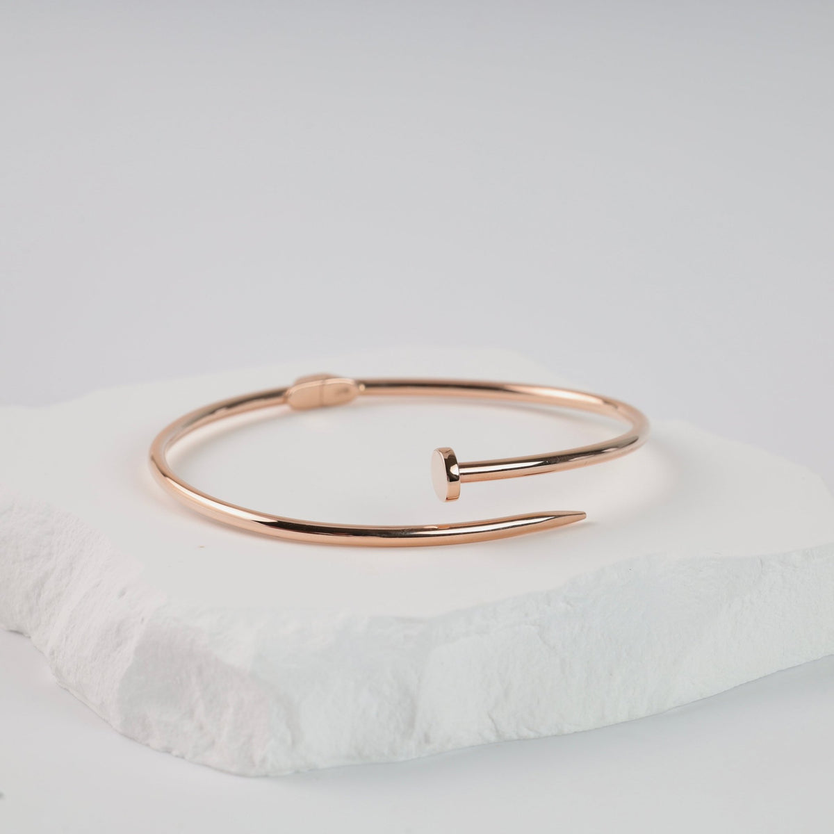 14K rose gold nail bangle bracelet front view on a white cushion