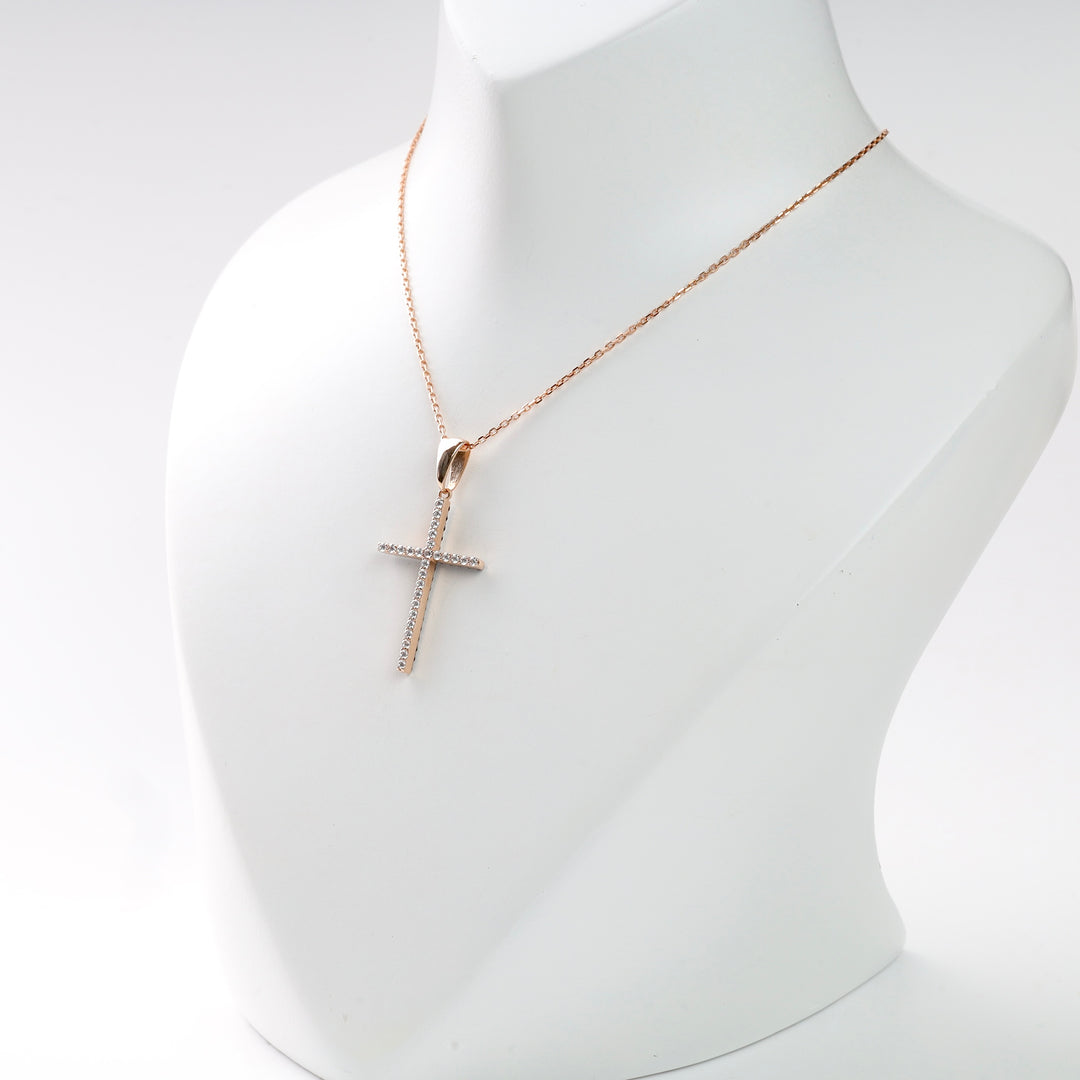 Gold chain necklace with a diamond cross pendant displayed on a white stand.
