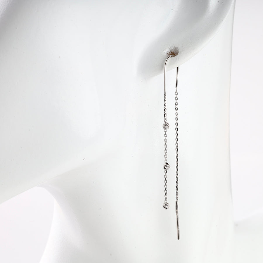 Single silver threader earring with a delicate chain and small knot details on a white mannequin display.