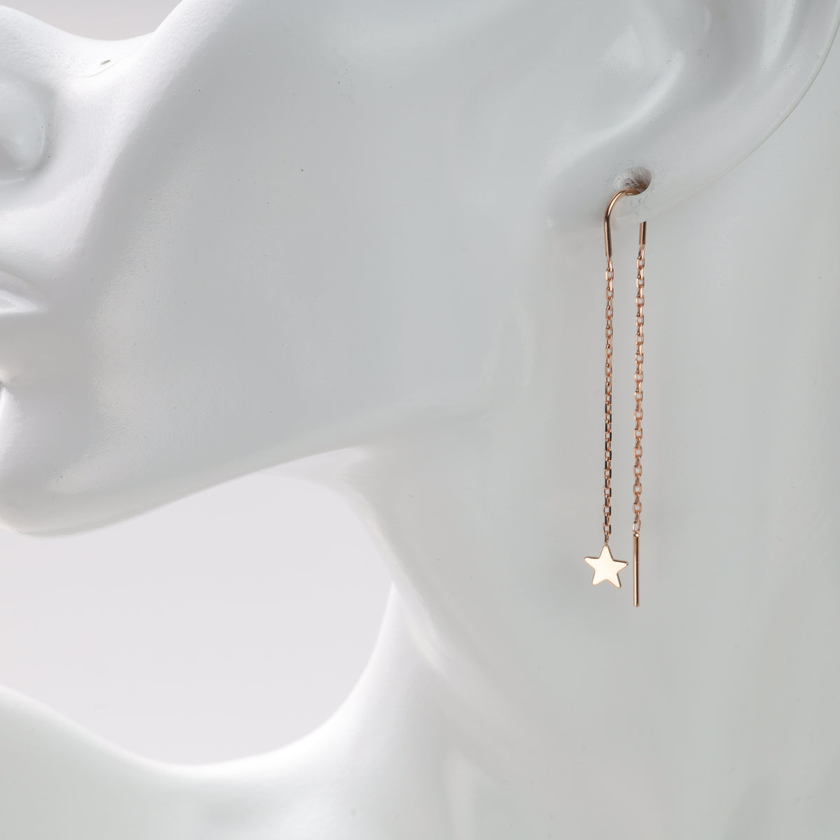 Gold chain earrings with star charm on mannequin.