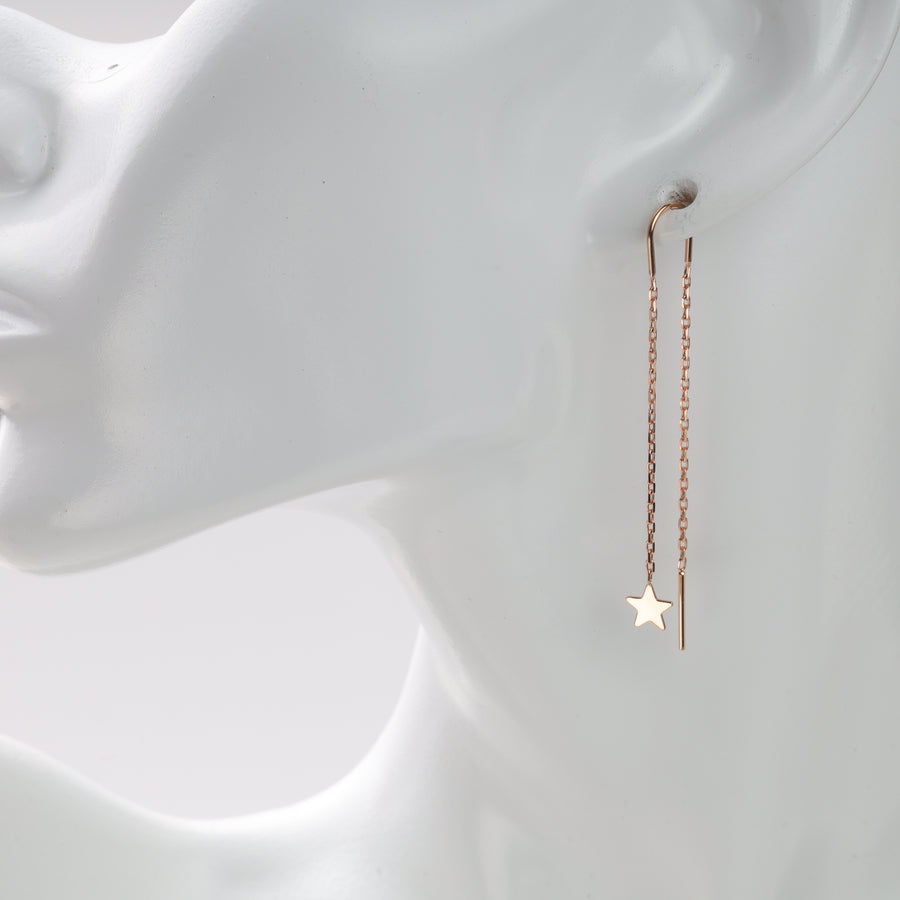 Gold chain earrings with star charm on mannequin.