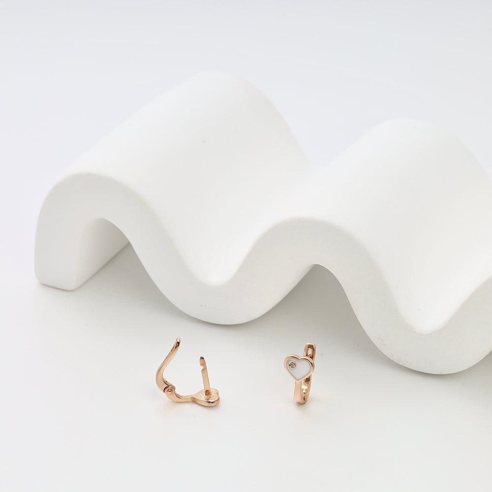 14k gold heart huggie earrings with white enamel on a white display, Ukrainian Jewelry, dainty gold hoop earrings for women.