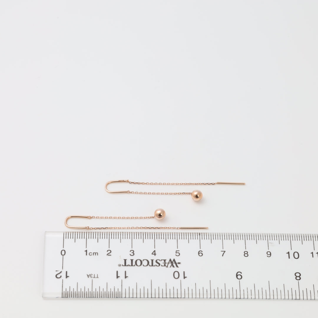 Pair of rose gold threader ball earrings with fine chains shown beside ruler, minimalist drop jewelry, Ukrainian Jewelry for women.