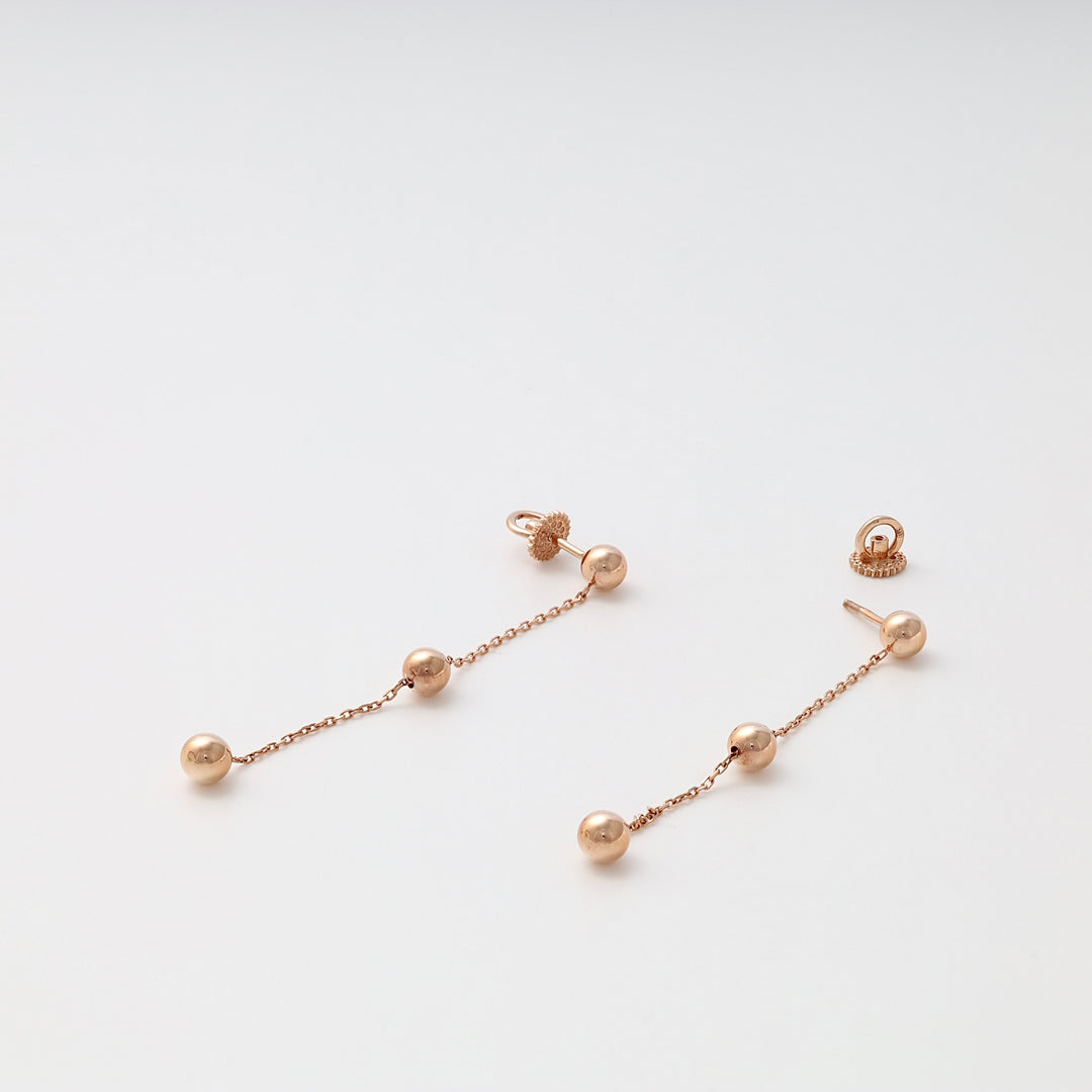 Rose gold drop earrings with three ball beads on each chain, shown on a white background.
