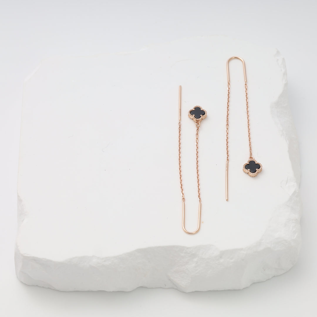 14k gold threader earrings with black clover charms on a white stone display, delicate drop earrings Ukrainian Jewelry.