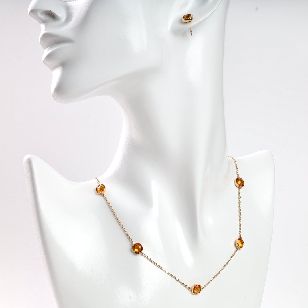 Gold chain necklace with amber gemstones on mannequin.