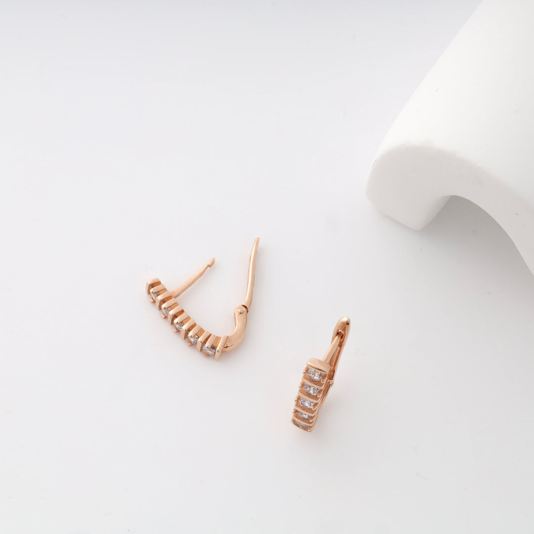 Rose gold hoop earrings with diamond accents on white background.