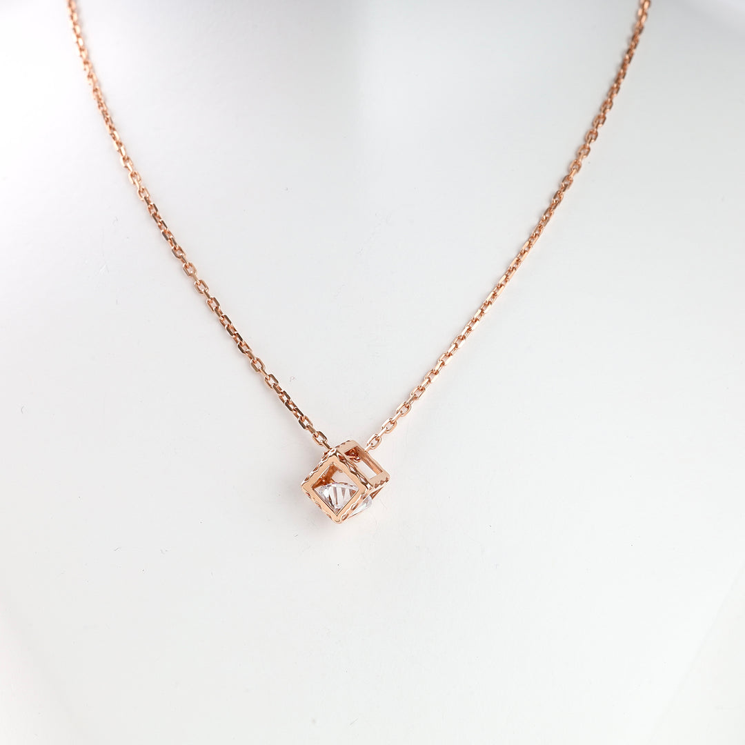 Rose gold chain necklace with a geometric square pendant holding a clear crystal, displayed on a white bust.
