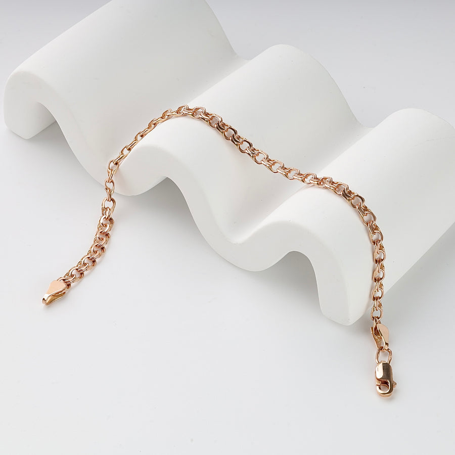 Rose gold chain bracelet with lobster clasp, displayed on a white curved stand.