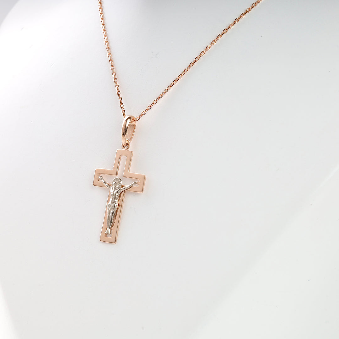Rose gold and silver crucifix necklace with Jesus motif displayed on a white bust, religious jewelry pendant.